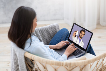 Young female patient using laptop, talking to her doctor about prescribed medicine online from home