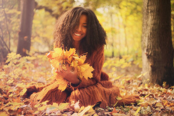 Young black woman relaxing in the autumn forest on a sunny day.