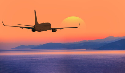 Airplane flying above tropical sea at amazing sunset