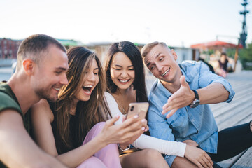 Cheerful multiracial friends surfing smartphone in park