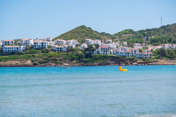 Menorca, Spain - August 6, 2020: Nice bay with an inflatable mega yellow duck, Cala Tirant, Fornells, Menorca, Balearic Islands. Spain.