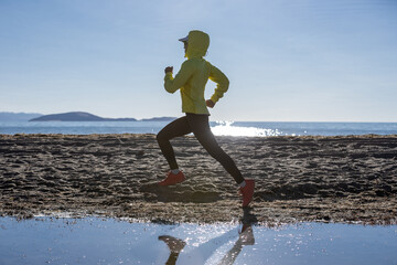 Woman trail runner cross country running on winter high altitude lakeside