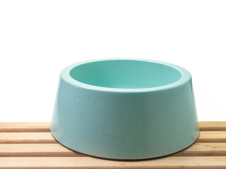 The close up of empty blue green plastic dog bowl, pet equipment with wood plank on white background.