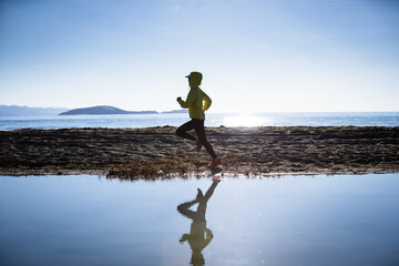 Woman trail runner cross country running on winter high altitude lakeside