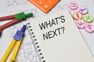 Top angle view of math compass, calculator and alphabet erasers written with question WHAT'S NEXT?. Business concept.