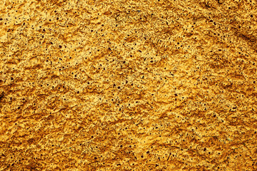 Closeup texture of old yellow paint on a concrete wall.