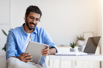 Arab Freelancer Guy Using Digital Tablet At Home, Having Break In Work
