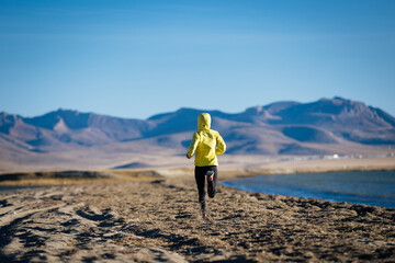 Woman trail runner cross country running on winter high altitude lakeside