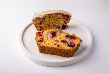 Two pieces of homemade cupcake with cranberries and icing sugar on a white plate on a light background, close up, copy space