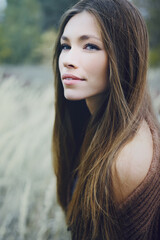 Closeup of a young cowboy woman in autumn dry grass. Western style.