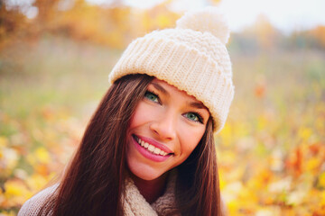 Happy young woman in a white sweater having fun in the autumn leaves in the forest. Beautiful appearance, fashion model.