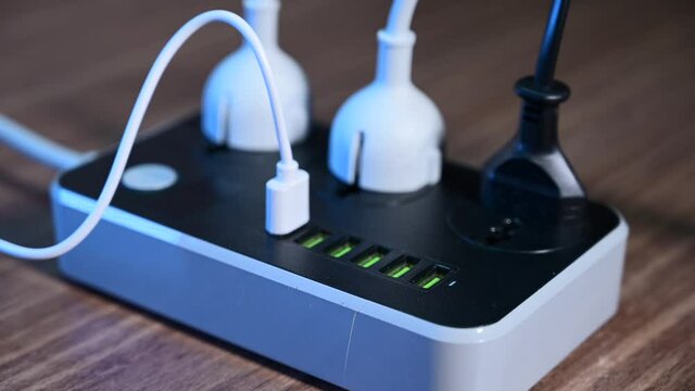 Close-up of a male hand plugging cables into a power outlet. Modern convenient multi-port usb charger for devices. 