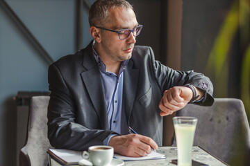 Businessman checking the time while working in a cafe.