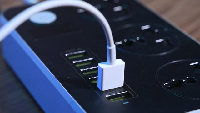 Close-up macro of a male hand plugging cables into a power outlet. Modern convenient multi-port usb charger for devices. 