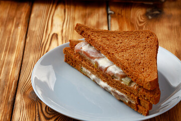 Toasted rye sandwich in plate on wooden table