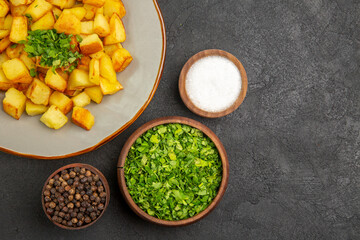top view tasty fried potatoes inside plate with seasonings on a dark background color food kitchen photo meal