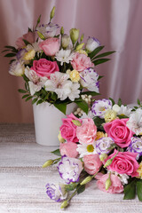 two bouquets of roses, daisies, lisianthus, chrysanthemums, unopened buds on a plank table and a background of pink silk fabric with pleats.