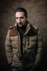 Portrait of a man. A man in a winter jacket. Winter fashion. Portrait on a brown background