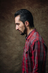 Obraz na płótnie Canvas Male portrait in profile. man in a red shirt. Portrait on a brown background.