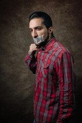 Portrait of a man. The mouth is sealed with tape. The guy in the red shirt. The social problem of silence. Deprivation of the right to vote