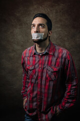 Portrait of a man. The mouth is sealed with tape. The guy in the red shirt. The social problem of silence. Deprivation of the right to vote