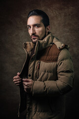 Portrait of a man. A man in a winter jacket. Winter fashion. Portrait on a brown background