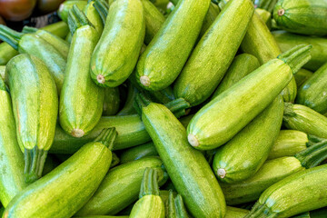 A group of green courgettes for sale at an outdoor market.