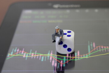 Simple Conceptual Photo, illustration for Gambler Investor Mini Figure Toy businessman Sadly watching Graphic Candle Light Stick, Sitting at Big Plastic Dice