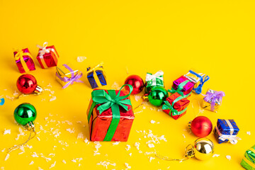 Gift box with a Christmas present on a yellow background, among the New Year's decorations