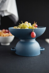 Juicy grapes in a blue bowl on a dark background.