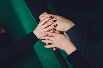 two man and three women holding hands on a table implying a polyamory relationship or love triangle.