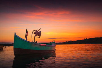 Obraz premium Fishing boat on sea shore and dramatic colorful sunset