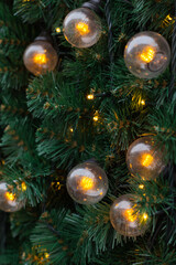 yellow light bulbs, a large glowing garland on the background of green needles from the New Year tree