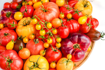 Different tomatoes on white. Vegetables of different varieties