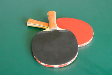 pair of black and red ping pong rackets on a green table background