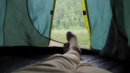Legs of a man resting in a tent against the background of the forest. - Powered by Adobe