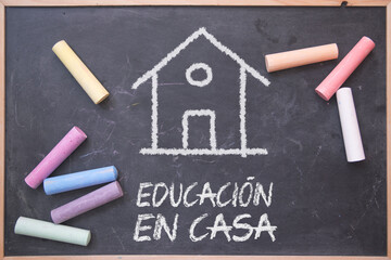 Home Schooling in Spanish on a blackboard with some chalks on it. Alternative education model.