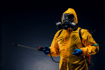Portrait of a man in a yellow chemical protection suit holding a sprayed disinfectant