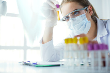 Portrait of pretty female laboratory assistant analyzing a blood sample at hospital