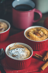 Three apple pies in ceramic baking molds with red napkin ramekin on dark wooden table. Shallow depth of the field.