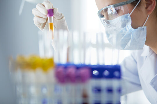 A medical or scientific researcher or doctor looking at a test tube of liquid green solution in a laboratory