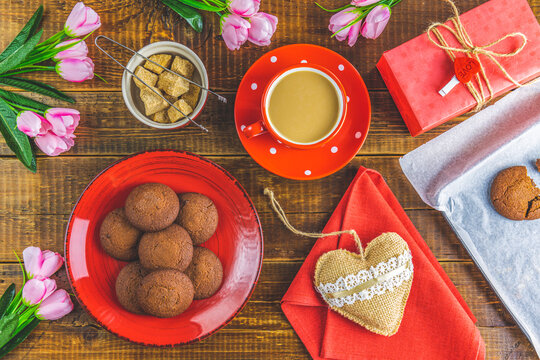 Morning cup of coffee, chocolate cake, gift or present box, candles and flower on wooden table from above. Romantic Valentines Day food background