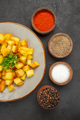 top view tasty fried potatoes inside plate with seasonings on dark background color oil kitchen dinner food photo