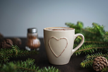 Christmas coffee with cinnamon on a wooden table. Spruce branches and cones, chocolate spoon.