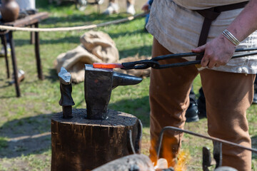 Hot metal red lies on the anvil. The blacksmith forms a knife blade