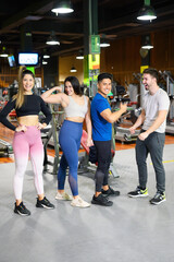 Obraz na płótnie Canvas Group of four happy female and male young adults standing together as good friends, posing in gym. High quality photo