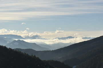 Nebelige Berglandschaft mit Wolken und Sonne, Horizont in der Weite sich verlierend