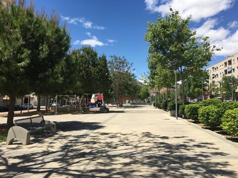 Outdoor recreation area with trees, benches and a play area for children.