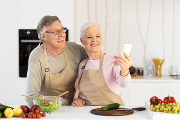 Obraz na płótnie Canvas Joyful Elderly Spouses Making Selfie Having Fun Cooking In Kitchen