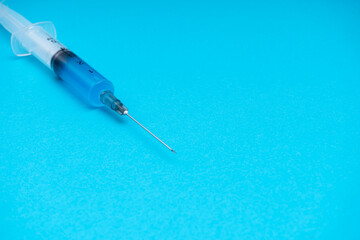 Medical syringe with vaccine on a blue background